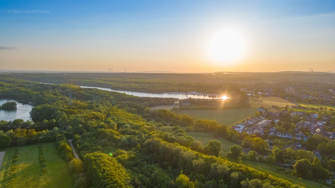 Drohnenaufnahme bei Sonnenuntergang über Wald, Seen und Wohngebiet in Hürth