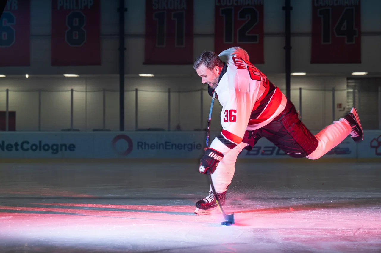 Eishockeyspieler beim Schuss auf dem Eis im roten Licht